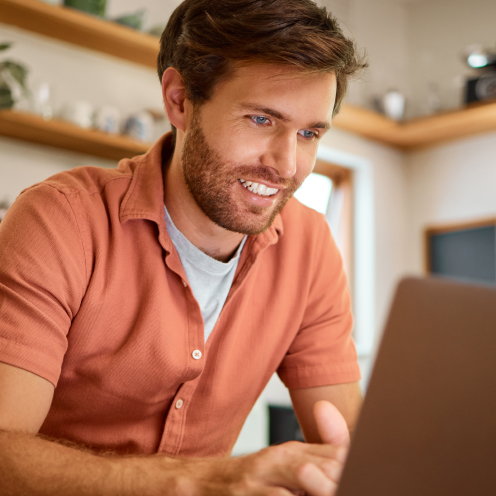 Mann mit Hemd arbeitet konzentriert an Laptop in gemütlichem Innenraum