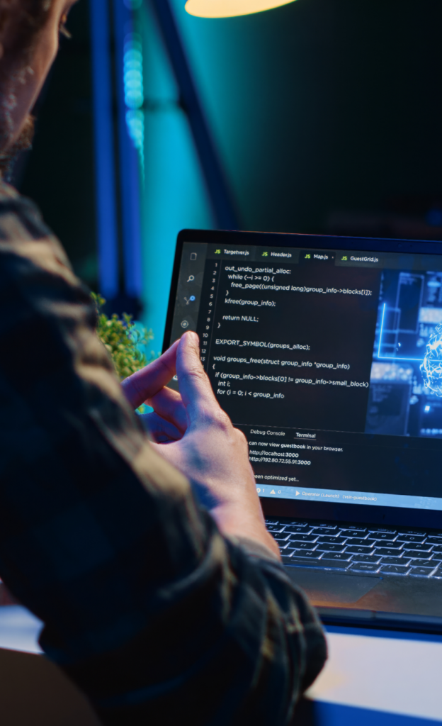 Person arbeitet abends an Laptop mit Programmiercode auf Bildschirm