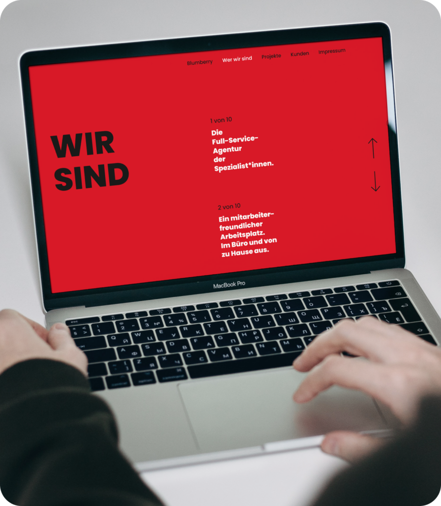 Laptopbildschirm mit rotem Hintergrund und Texten zu einer Full-Service-Agentur und Mitarbeiterfreundlichkeit.